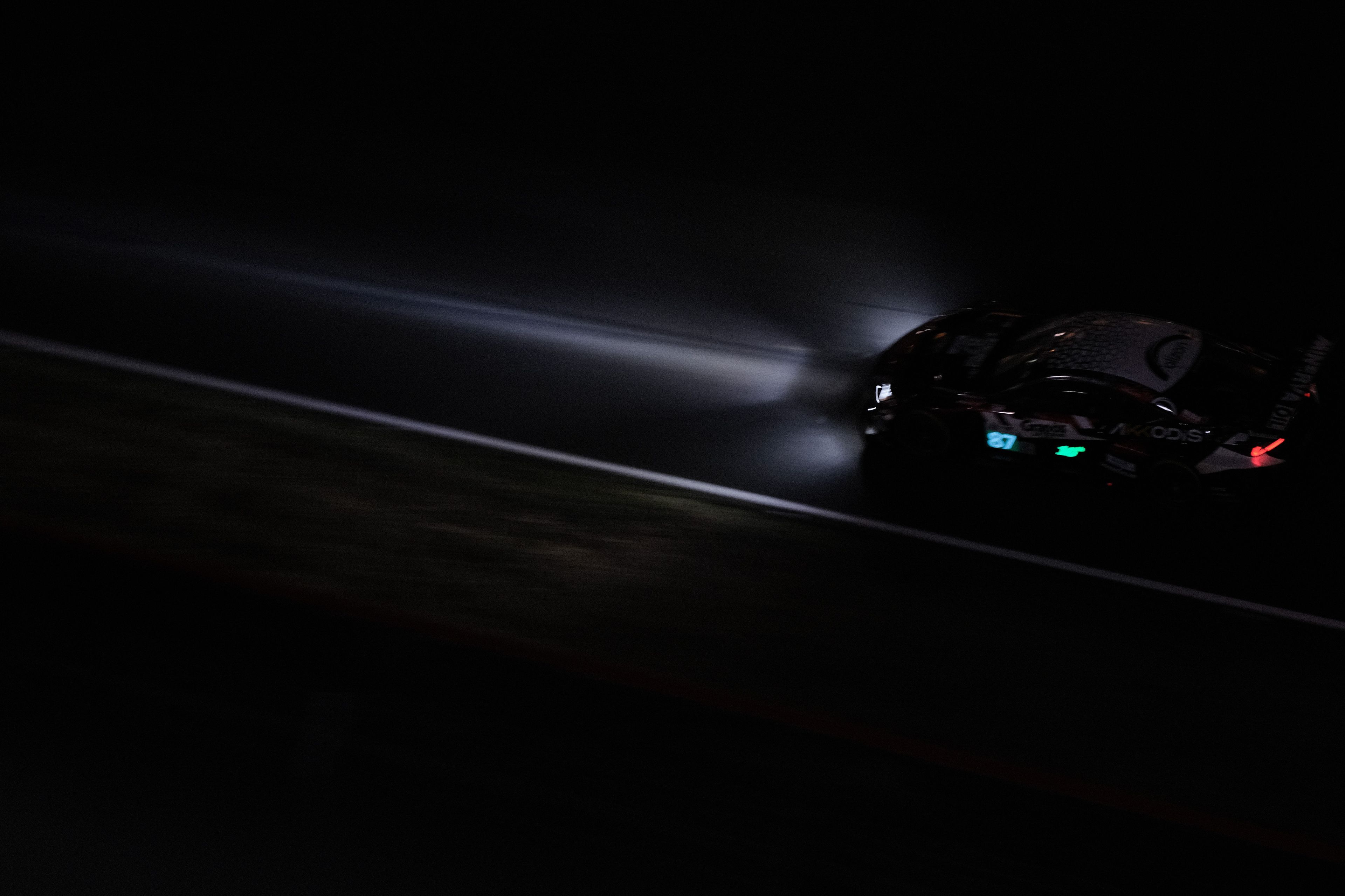 Vehicle on a dark road at dusk or night, moody automotive scene.